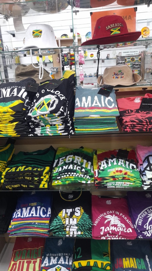 Wall of folded Jamaica-themed t-shirts and caps